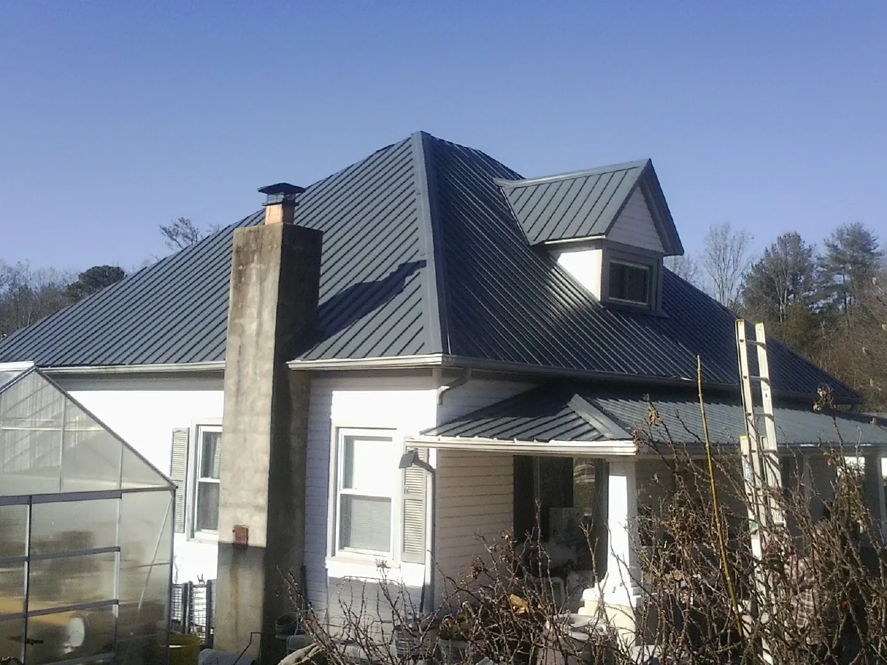Dark blue standing seam metal roof on a white farmhouse with dormer — Slate & Tile Roof Repair by Roofing Brothers in Elk River