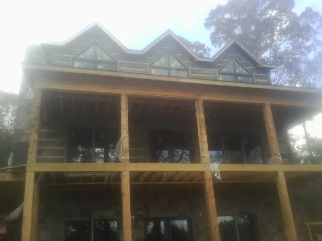 Dormers and porch framing on a large log home under construction — Roof Coating work by our crew in Elk River