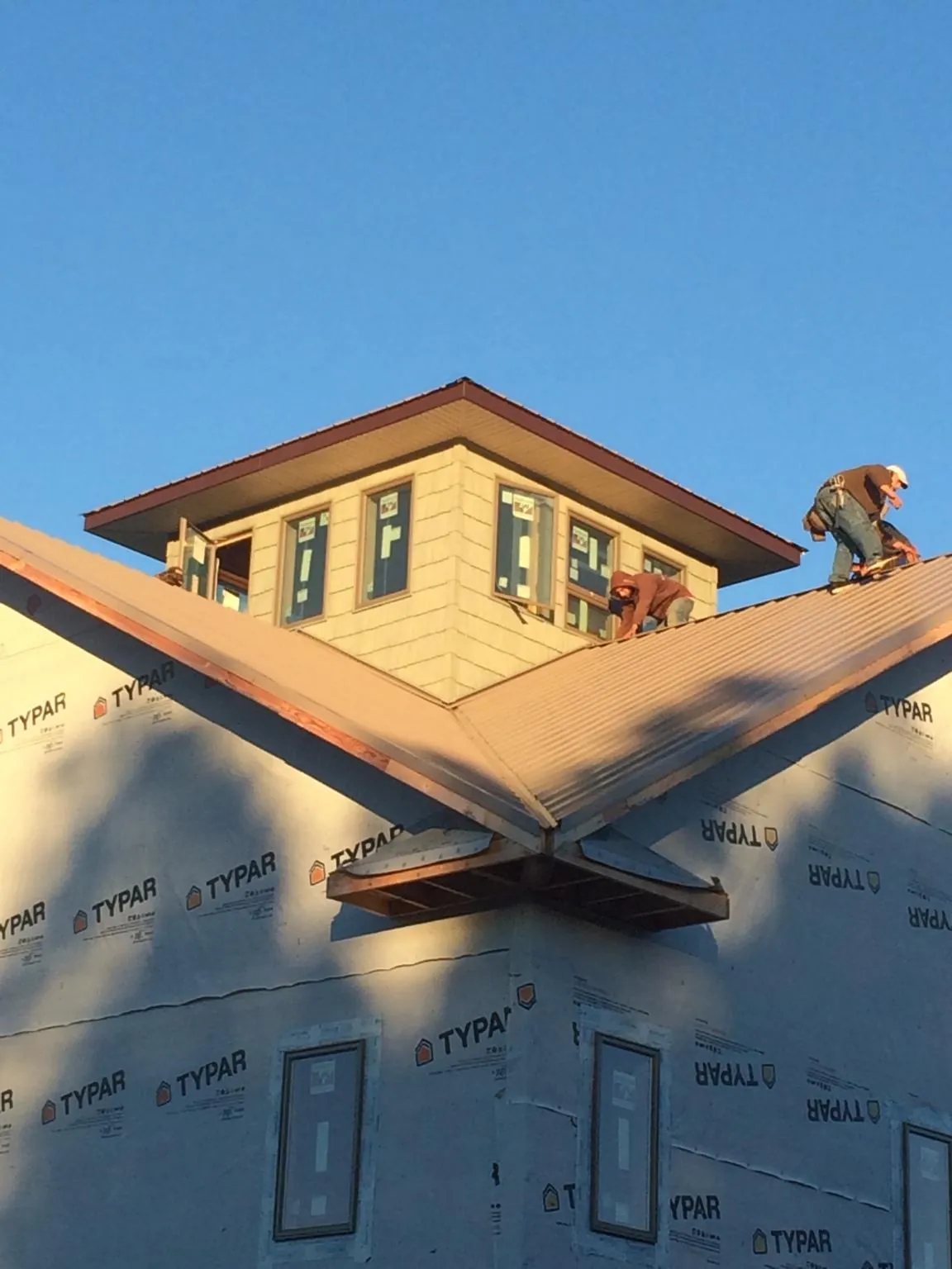 Roofers working around a rooftop cupola on a new metal roof at sunset — Roof Waterproofing in Elk River by Roofing Brothers
